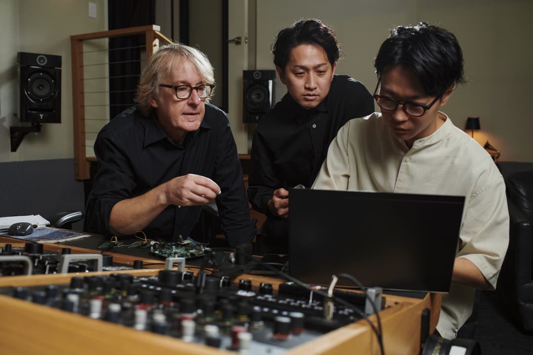 Trois ingénieurs du son en studio travaillant sur les écouteurs WF-1000XM6, observant un laptop près d'une console de mixage