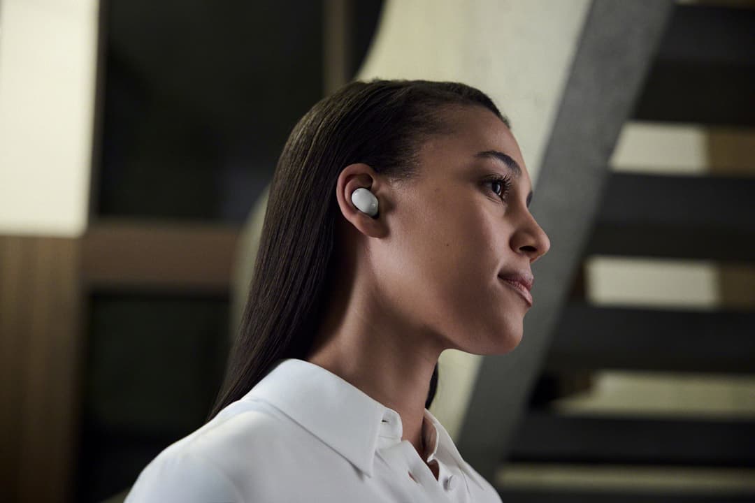 Écouteurs Sony WF-1000XM6 blancs portés par une femme, vue de profil