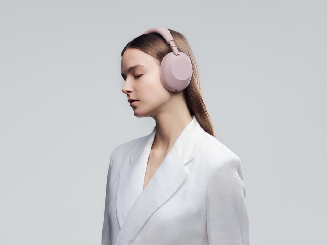 Casque sans fil Sony WH-1000XM6 rose poudré porté par une femme en blazer blanc