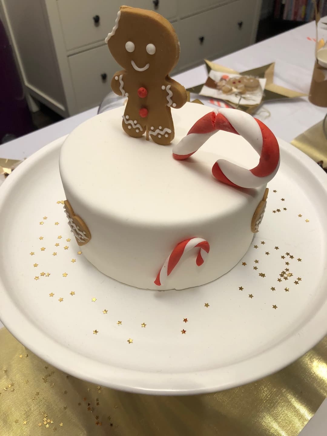 Gâteau blanc orné d'un bonhomme en pain d'épice, de cannes de Noël rouges et blanches, et d'étoiles dorées