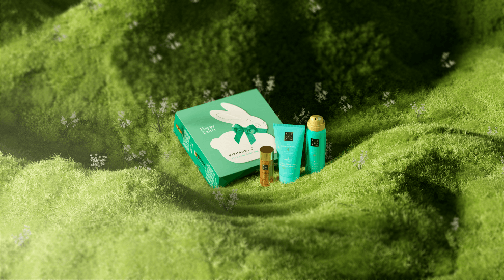 Coffret cadeau Rituals vert en forme de lapin, avec ruban vert, entouré de produits de beauté et bien-être sur un lit de mousse