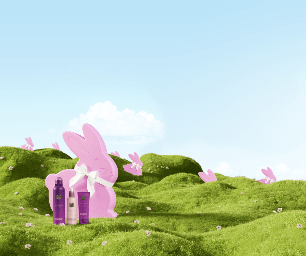 Coffrets de soins Rituals de couleur rose en forme de lapin sur un paysage vallonné vert avec fleurs et ciel bleu