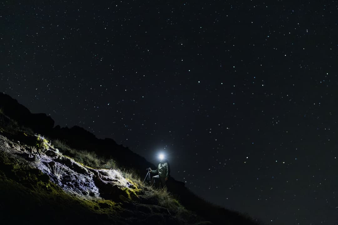 Photographe de nuit sur une montagne rocheuse, ciel étoilé au-dessus, objectif ultra grand angle Canon RF 14mm