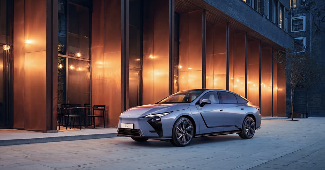 Nouvelle berline Lexus ES grise stationnée devant une façade moderne aux vitres teintées orange cuivré