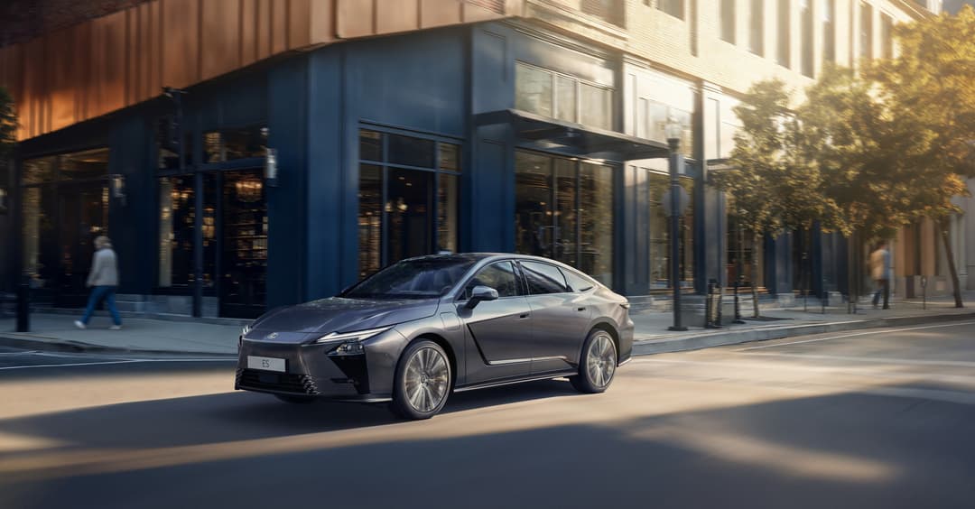 Lexus ES grise garée dans une rue urbaine devant des façades de verre et acier, en plein jour