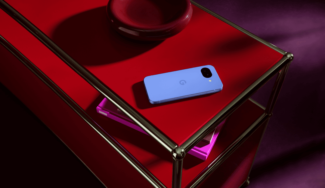 Google Pixel 10a bleu clair posé sur une surface rouge dans une structure de verre métallisée, éclairage rose et violet