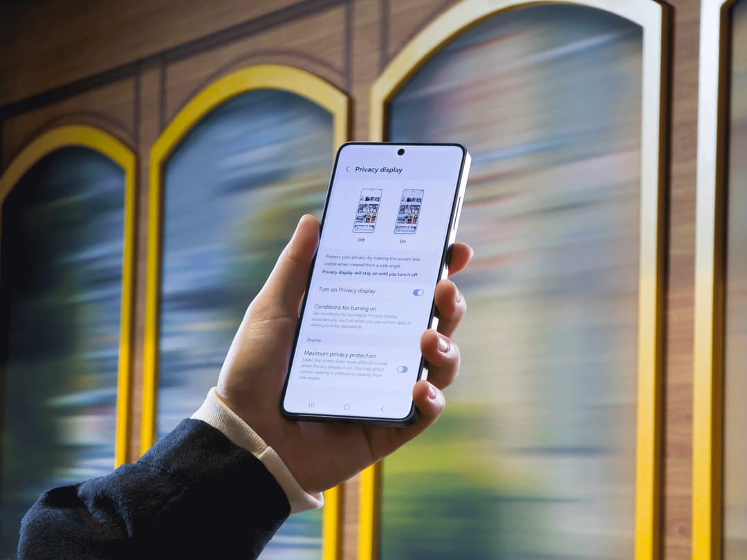 Samsung Galaxy S26 tenu en main affichant le menu de configuration du Privacy Display, devant une baie vitrée aux encadrements dorés