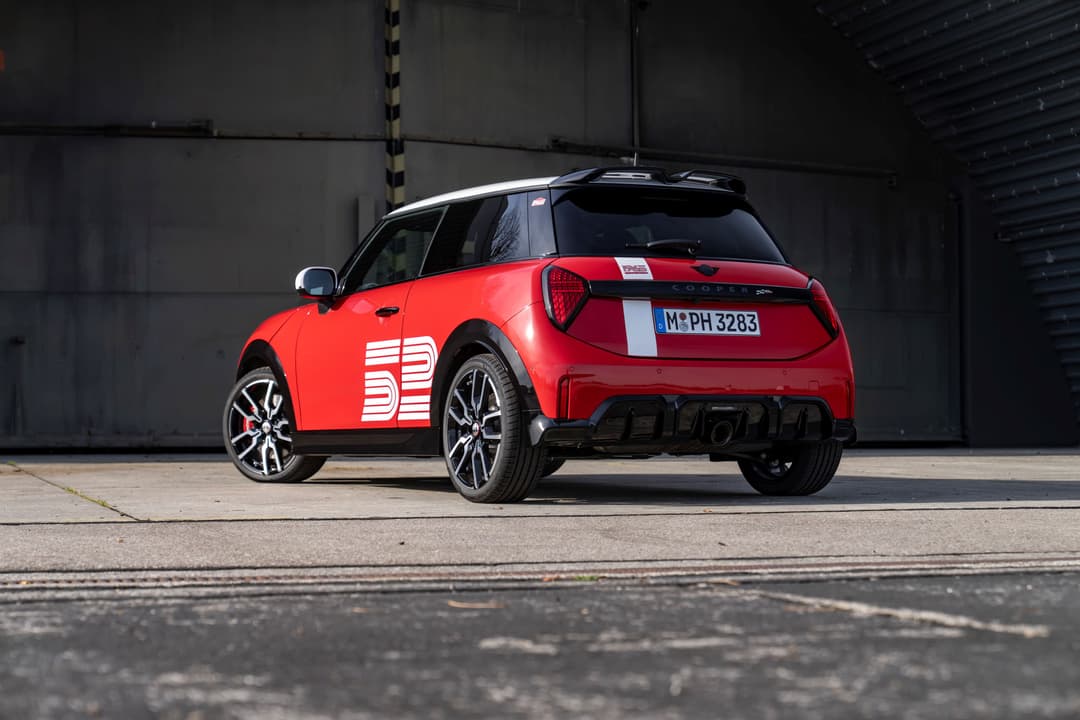 MINI 1965 Victory Edition rouge vue de trois quarts arrière, avec le numéro de course blanc « 65 » sur la carrosserie, stationnée dans un garage