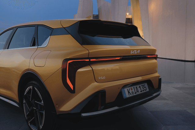 Kia K4 de couleur or vue de trois quarts arrière, avec ses feux arrière rouges allumés