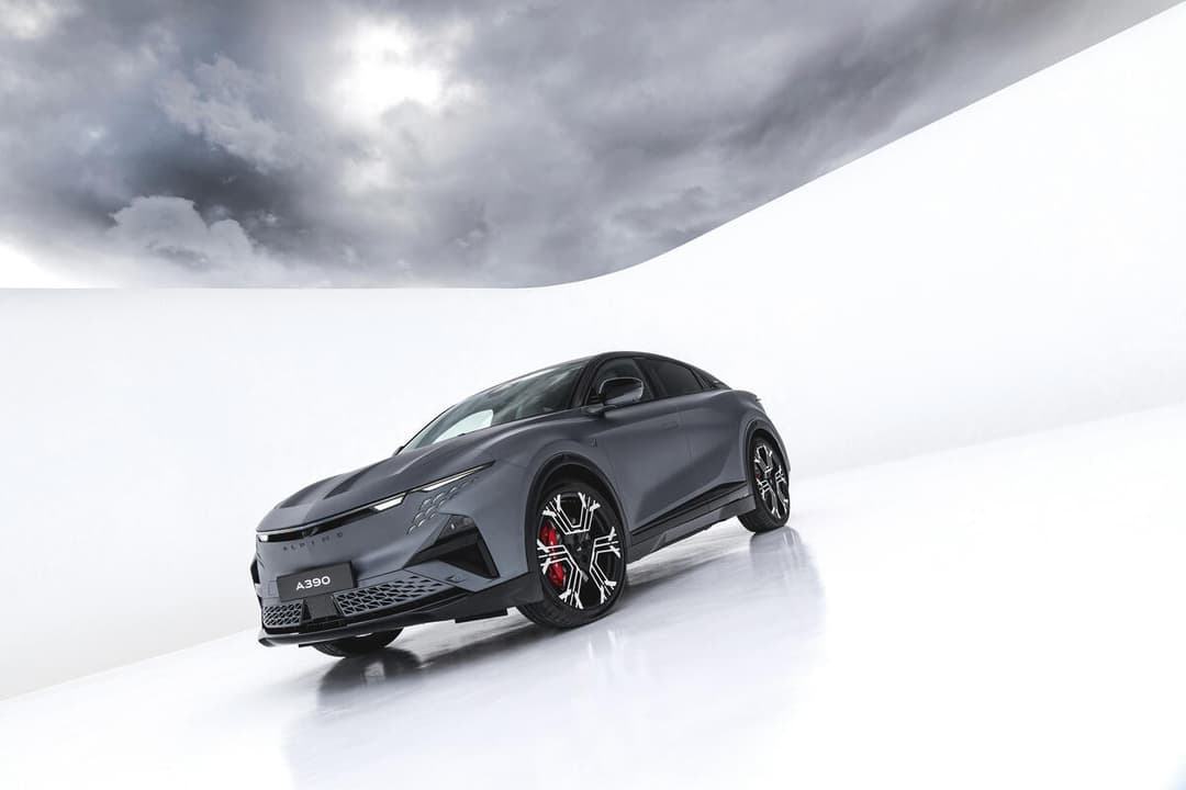 Alpine A390 GT, sport fastback gris anthracite, présenté de trois quarts sur fond blanc et ciel nuageux
