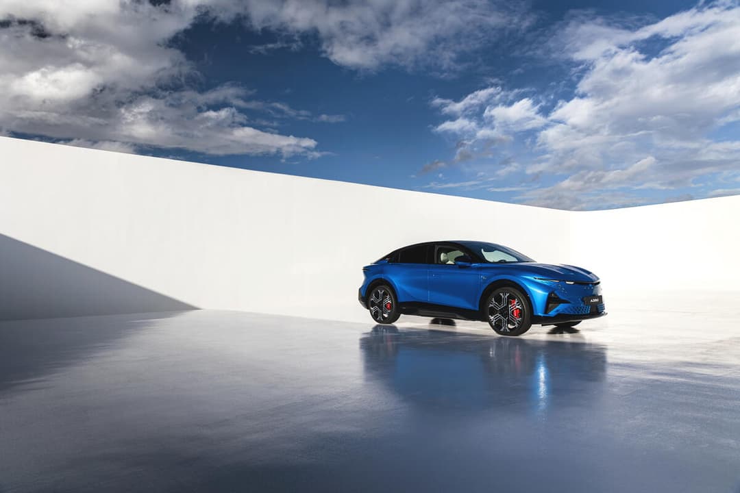 Alpine A390 GT bleu électrique, sport fastback, profil droit sur sol gris clair sous ciel nuageux