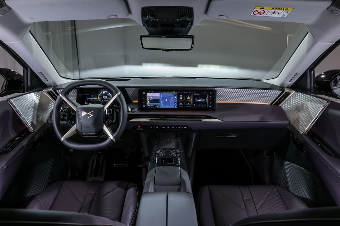 Habitacle du DS N°7 avec volant en X signature de la marque, écrans numériques et finitions premium en matériaux nobles