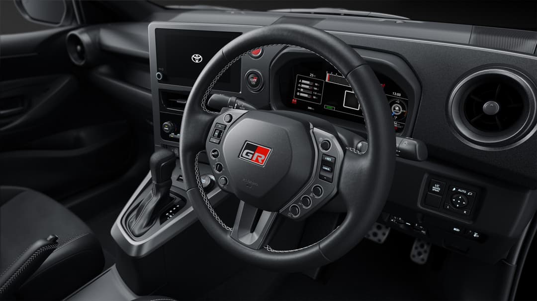 Volant sport redessiné de la GR Yaris avec logo GR rouge, commandes intégrées et tableau de bord digital, cockpit noir sportif