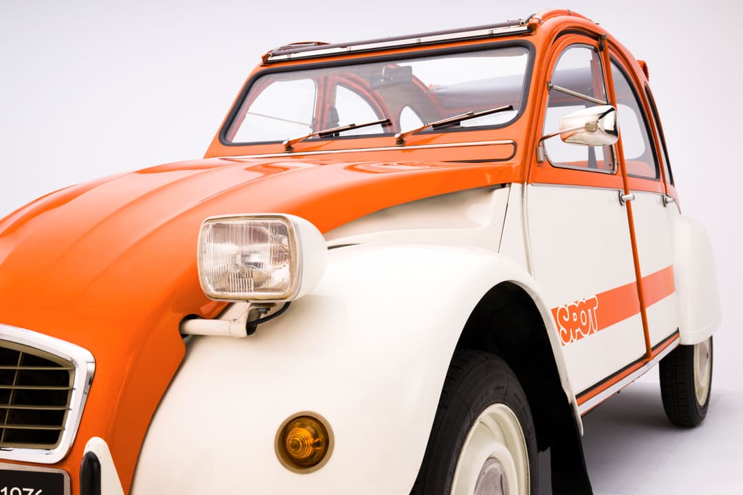 Citroën 2CV Spot orange et blanche aux ailes blanches, avec tendelet et portes rayées orange et blanc rappelant la toile d'un transat