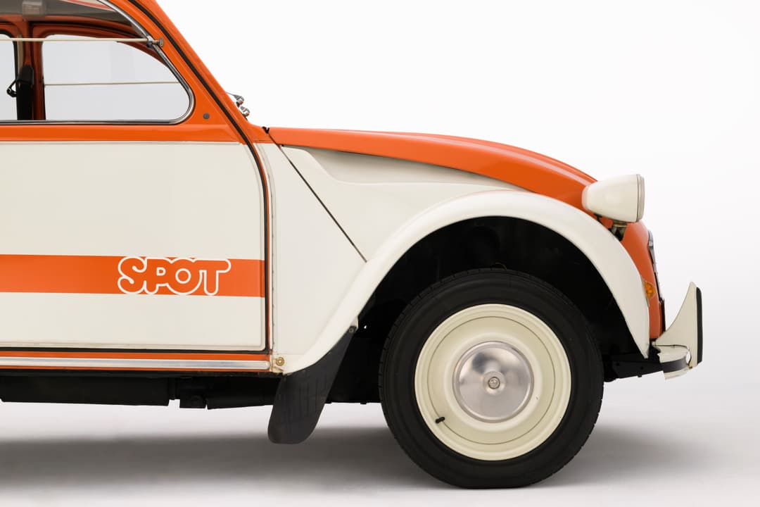 Citroën 2CV Spot bicolore orange et blanche, vue de profil trois-quarts avant sur fond neutre