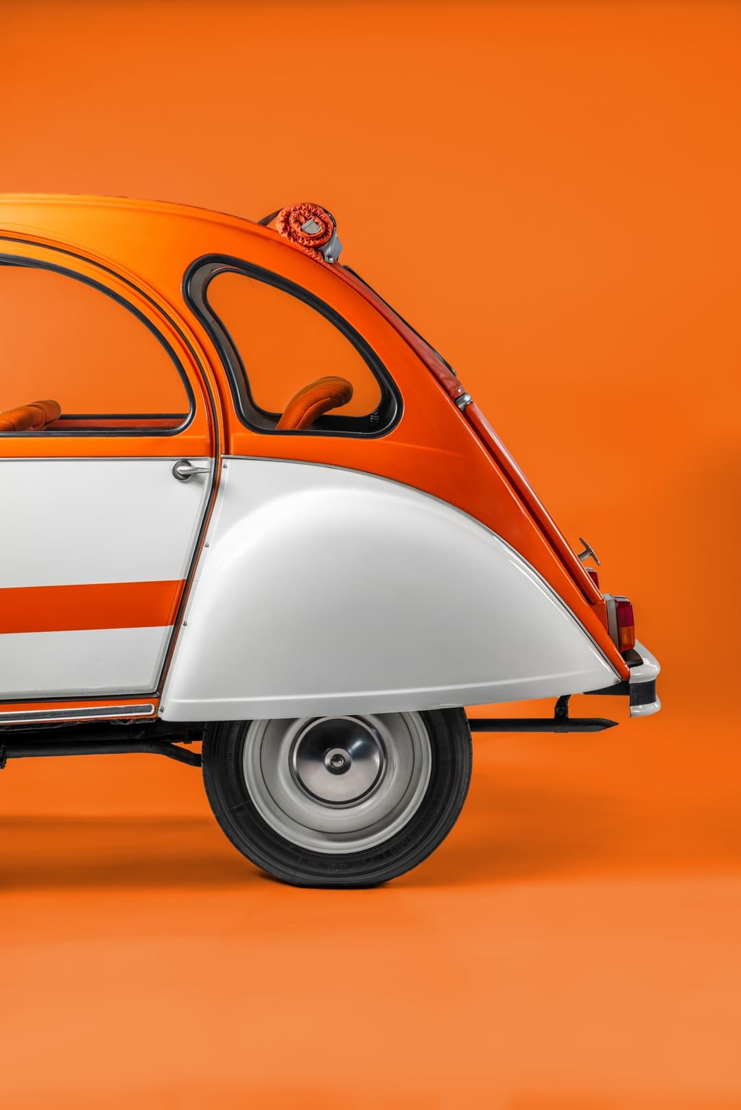 Citroën 2CV Spot orange et blanche de profil sur fond orange, vue latérale du modèle emblématique