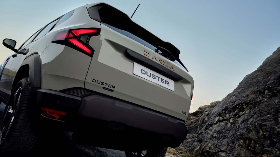 Dacia Duster hybrid 150 4x4 blanc de trois quarts arrière sur un terrain rocailleux