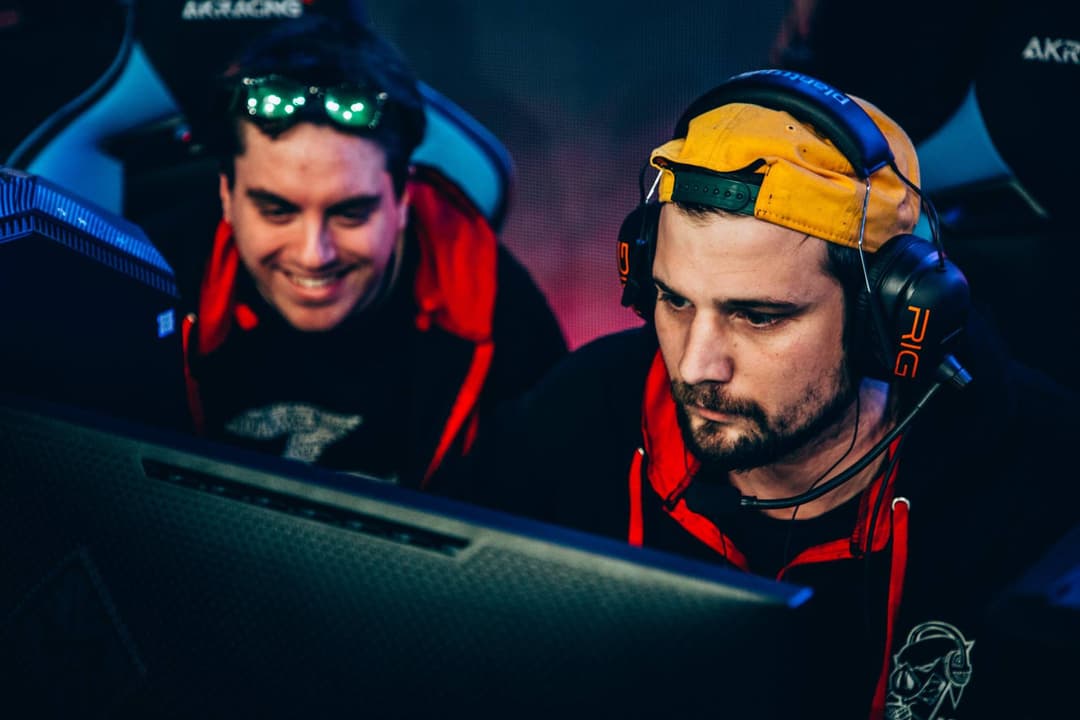 Deux streamers assis devant un écran, l'un portant des lunettes LED vertes, l'autre un casque jaune et noir avec microphone