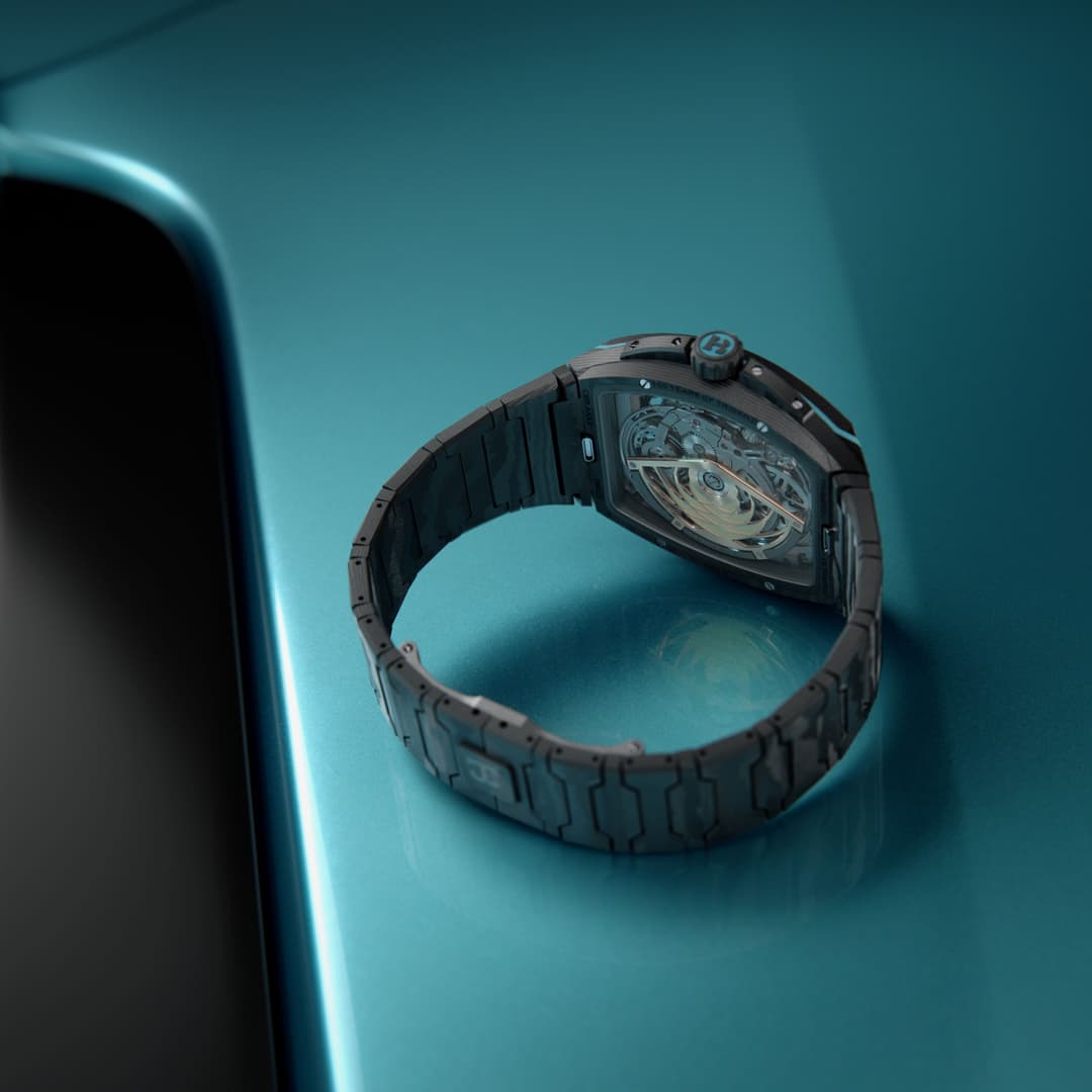 Montre Ultrafino Maserati avec boîtier noir, tourbillon visible et bracelet à mailles texturées sur fond bleu