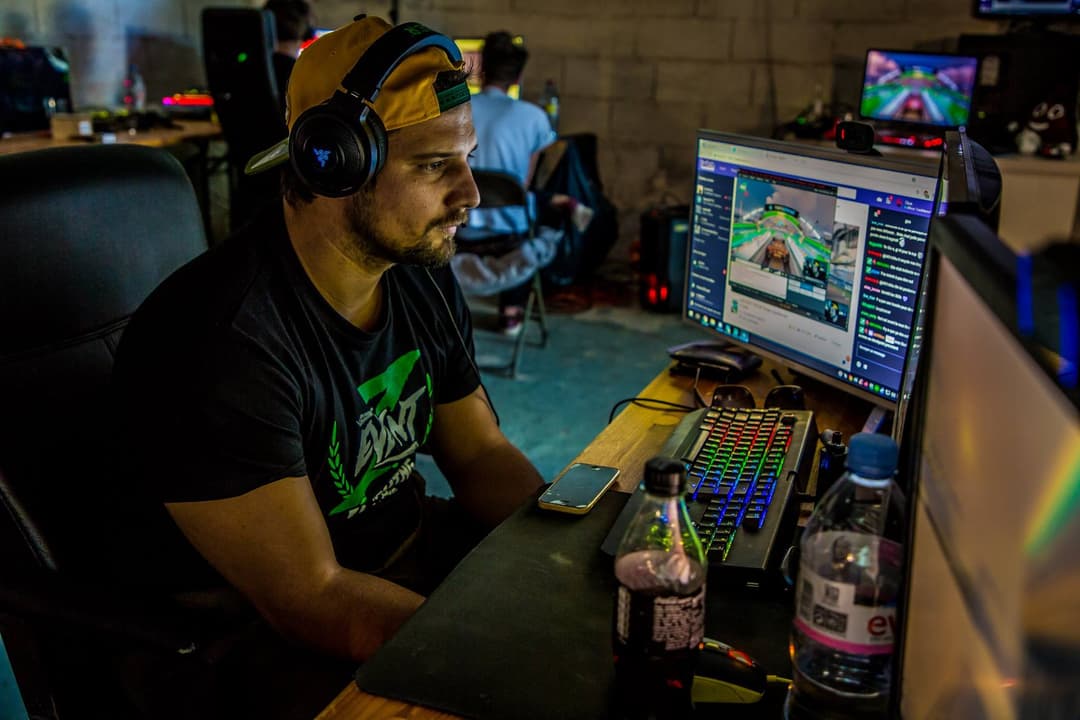 Gius casqué face à son écran gaming dans son setup de stream, avec clavier rétroéclairé et matériel professionnel