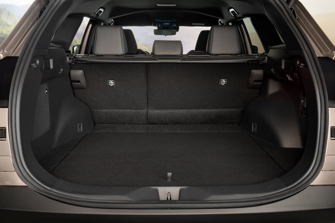 Coffre ouvert du Toyota bZ4X Touring, spacieux avec intérieur noir, portières relevées, montrant l'espace de rangement généreux