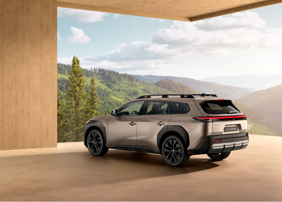 Toyota bZ4X Touring gris, SUV électrique, garé sous un auvent face à des montagnes boisées