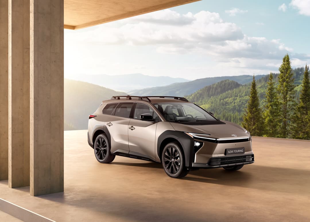Toyota bZ4X Touring blanc et gris, monospace électrique, garé sur une terrasse face à des montagnes boisées