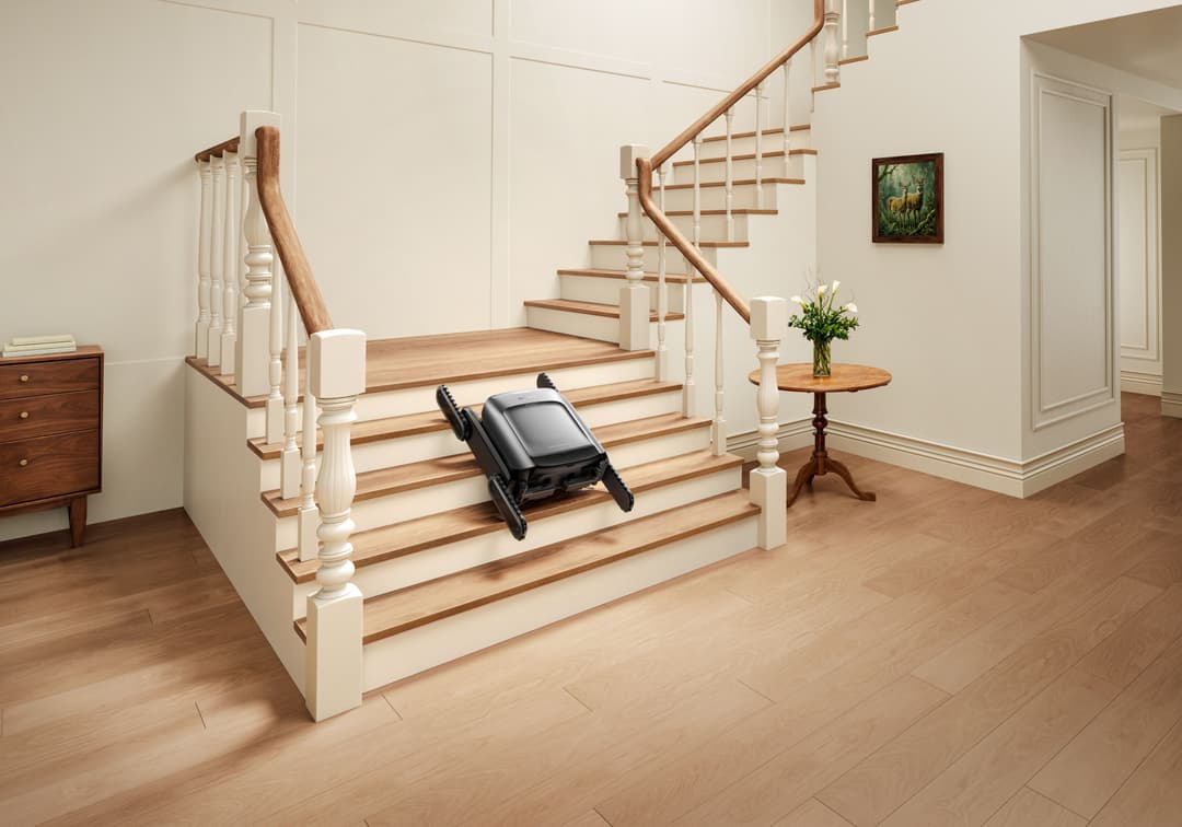 Robot aspirateur noir Dreame Cyber X montant un escalier en bois dans un intérieur moderne