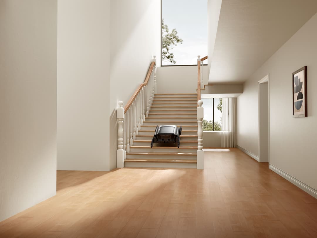 Robot aspirateur Dreame Cyber X montant les escaliers d'une maison moderne avec rampe en bois