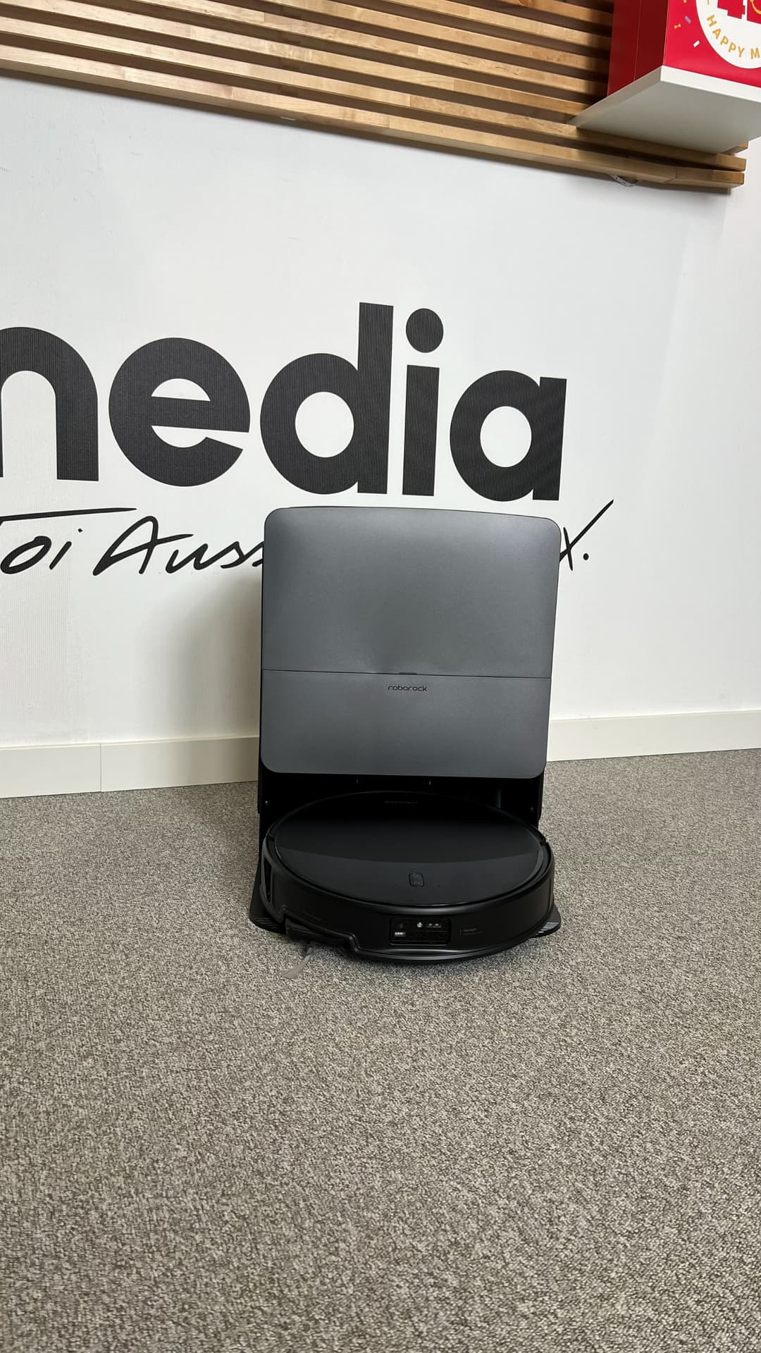Station RockDock grise et noire du Roborock Saros 20 posée sur un tapis gris en intérieur