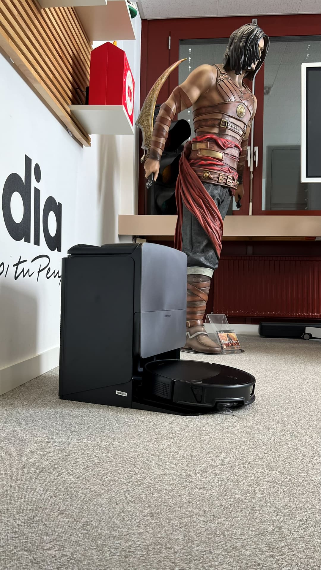 Roborock Saros 20, robot aspirateur noir avec station de vidage, dans un showroom auprès d'une figurine