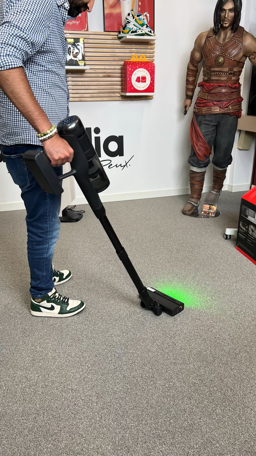 Roborock H60 Hub Ultra tenu à la main en position basse, buse active émettant une lumière verte, testée sur sol gris