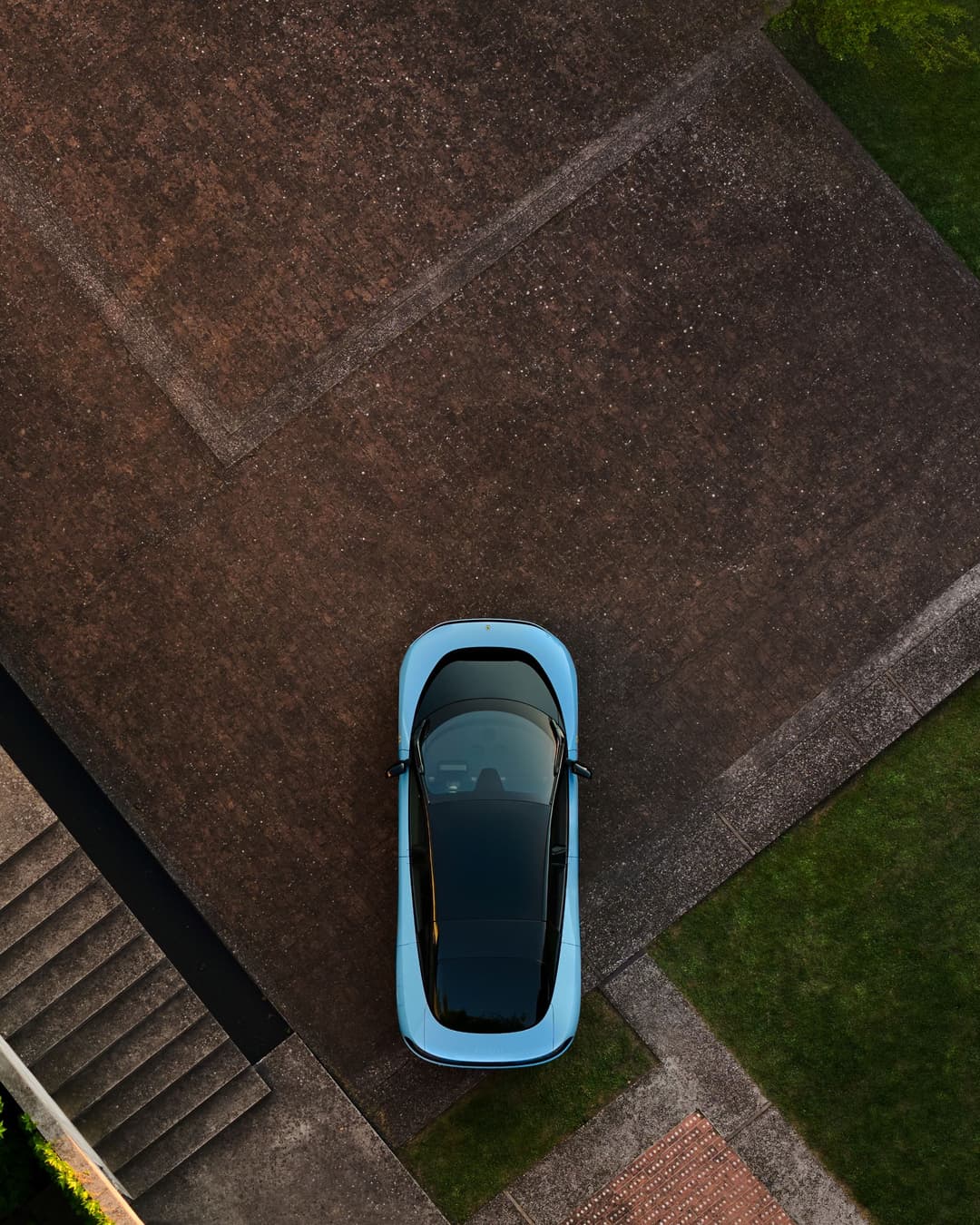Ferrari Luce bleu ciel vue de dessus sur allée pavée avec bordures vertes