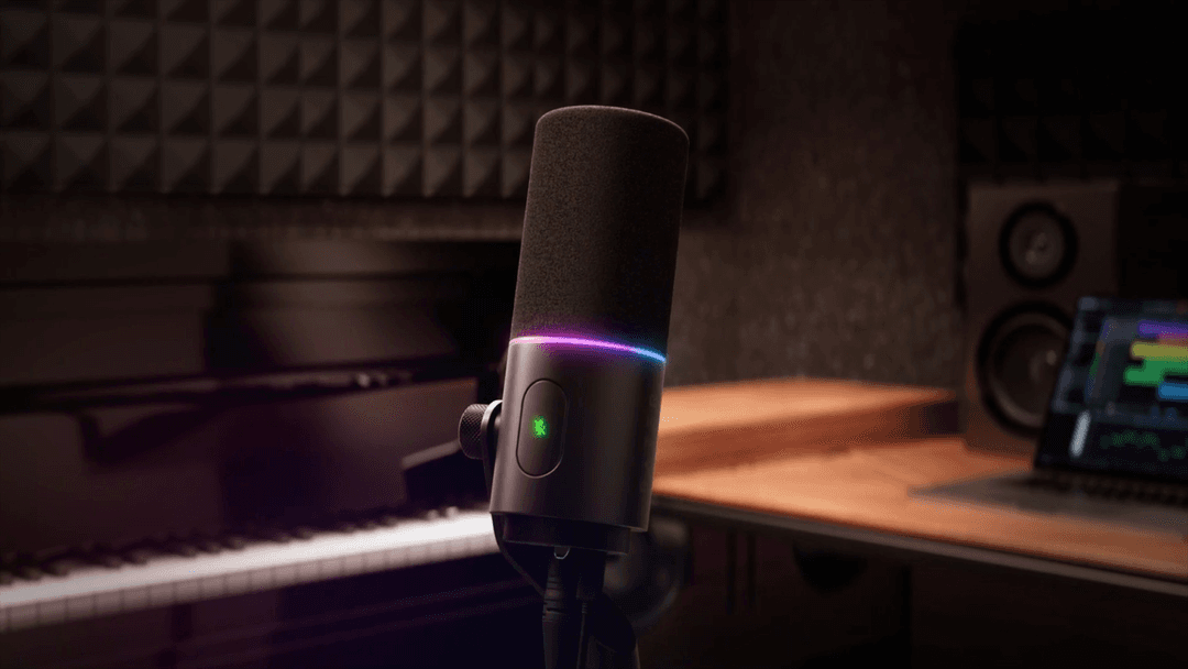 Microphone Seiren V3 Pro noir avec anneau lumineux rose et bleu, positionné sur un bureau de studio d'enregistrement équipé de matériel audio