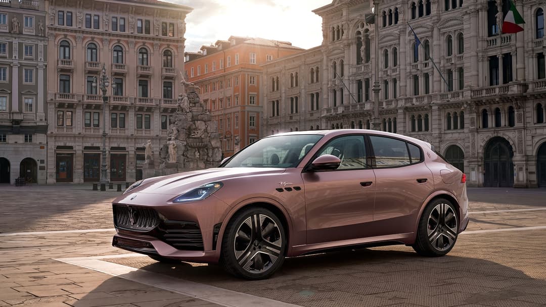 Maserati Grecale rose clair stationné sur une place italienne aux bâtiments historiques, drapeau italien visible