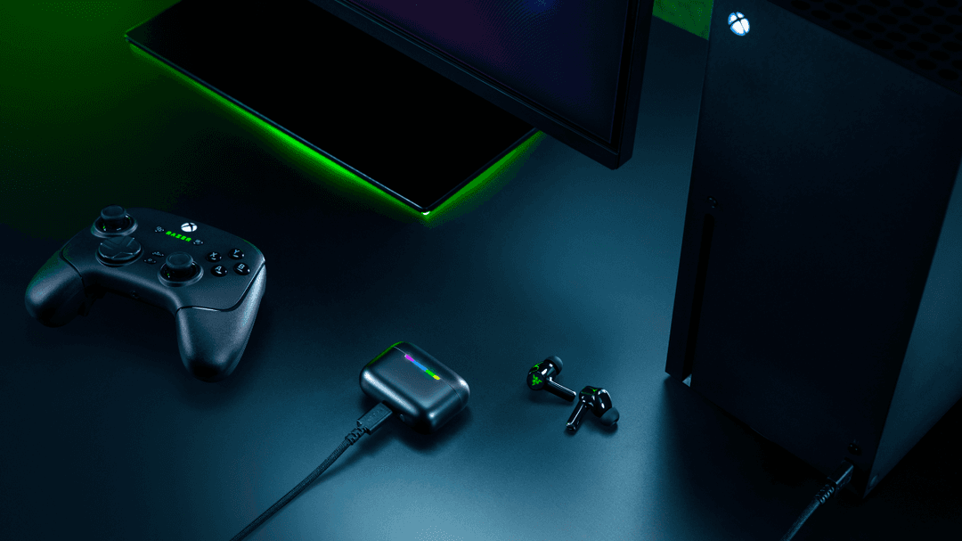 Écouteurs Razer Hammerhead V3 X HyperSpeed noirs avec boîtier de charge, contrôleur Xbox et écran gaming en arrière-plan, éclairage vert