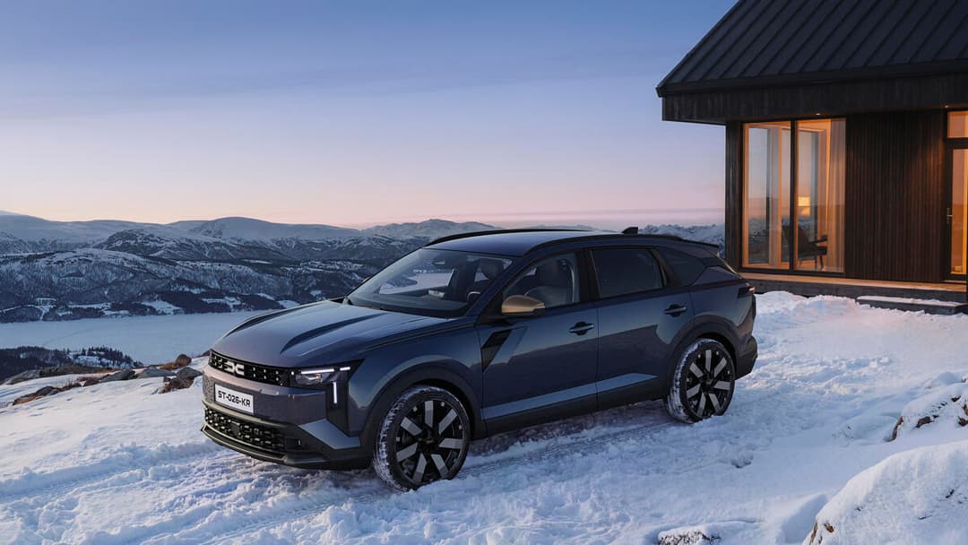 Dacia Striker bleu foncé garé sur la neige face à des montagnes enneigées et un lac gelé en arrière-plan