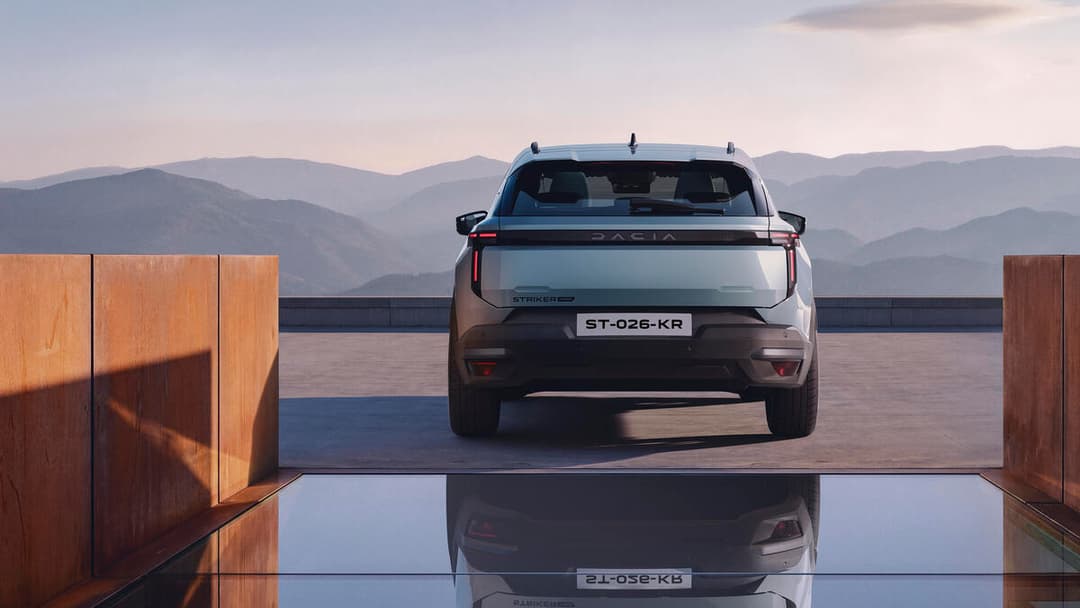 Dacia Striker de couleur grise vue de l'arrière, stationnée sur une plateforme avec des montagnes en arrière-plan