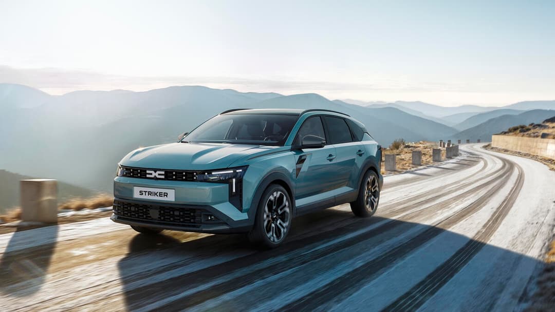Dacia Striker bleu turquoise circulant sur une route sinueuse en montagne avec paysage rocheux
