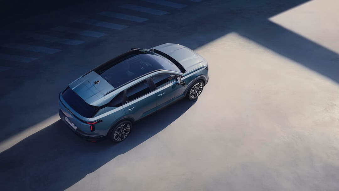Dacia Striker vue de dessus, berline grise avec toit panoramique, stationnée sur surface blanche et grise