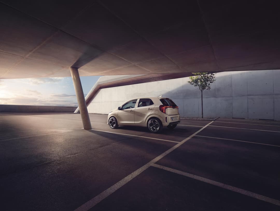 Kia Picanto beige garée sous un parking souterrain moderne, vue de profil