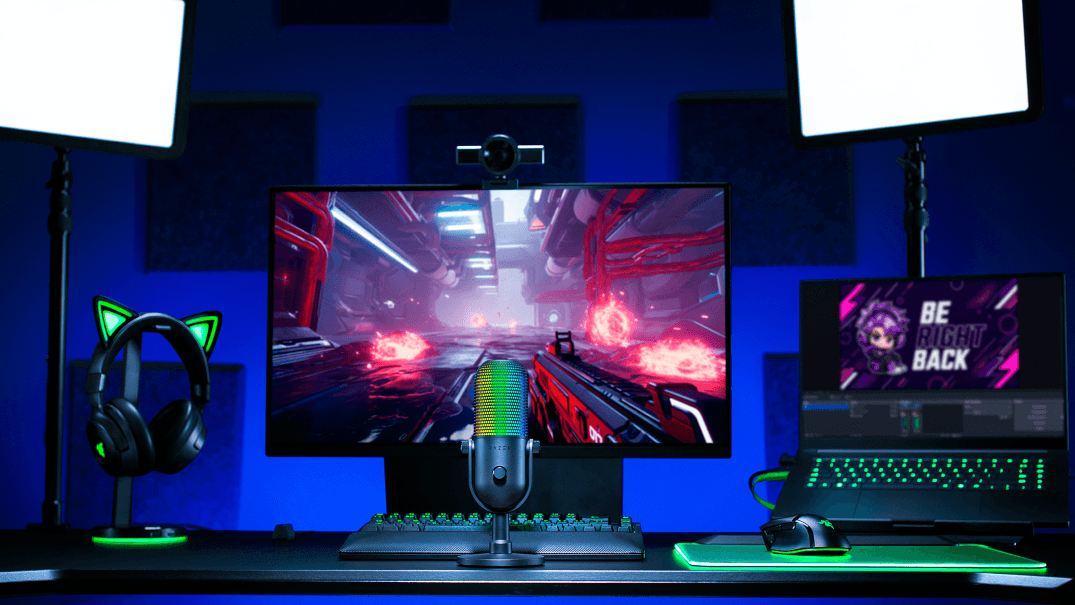 Microphone Razer Seiren V3 Chroma sur un bureau de gaming, avec éclairages RGB vert et bleu, entouré d'un casque, d'un écran et d'un clavier