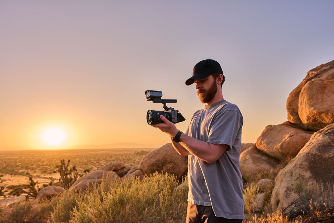 Opérateur tenant la caméra Sony FX5 à l'épaule au coucher du soleil dans un paysage désertique rocheux
