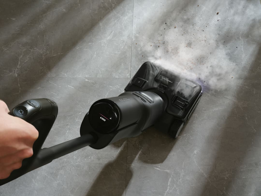 Roborock F25 Steam nettoyant un sol carrelé avec projection de vapeur, LED bleu visible et main tenant la poignée
