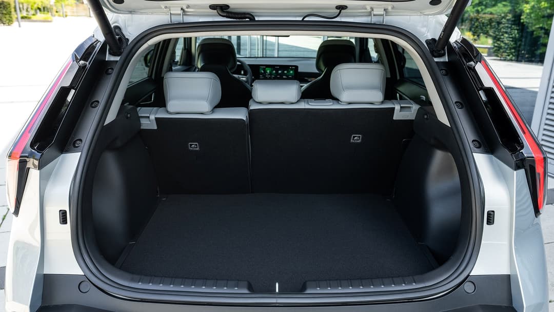 Kia Niro blanc, coffre ouvert montrant l'habitacle spacieux avec sièges avant gris clair et volume de chargement de 430 litres