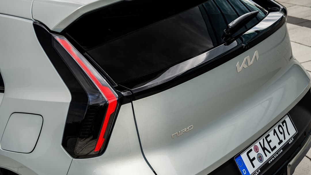 Kia Niro blanc vue de l'arrière, montrant le coffre ouvert, les feux rouges et le logo du modèle