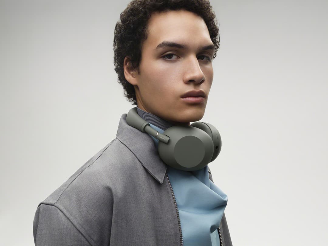 Casque Sony WH-1000XM6 coloris Olive porté par un homme de profil, en chemise grise sur fond blanc