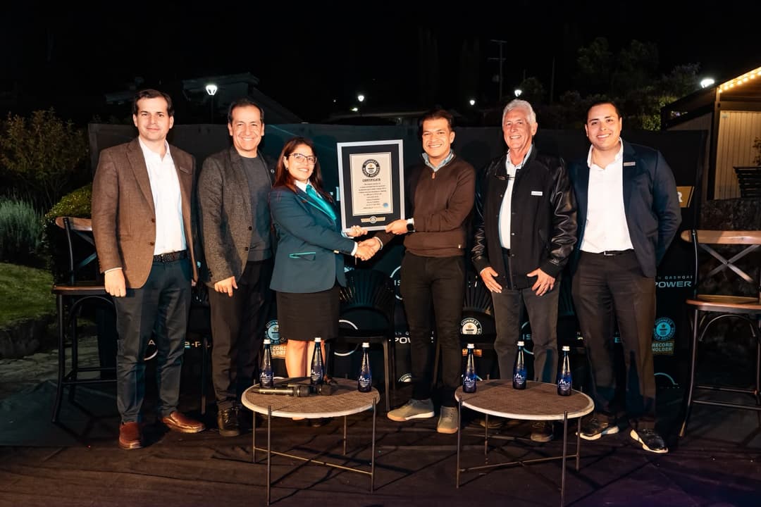 Six personnes en tenue habillée posent de nuit avec un certificat Guinness World Records devant un Nissan Qashqai e-POWER noir