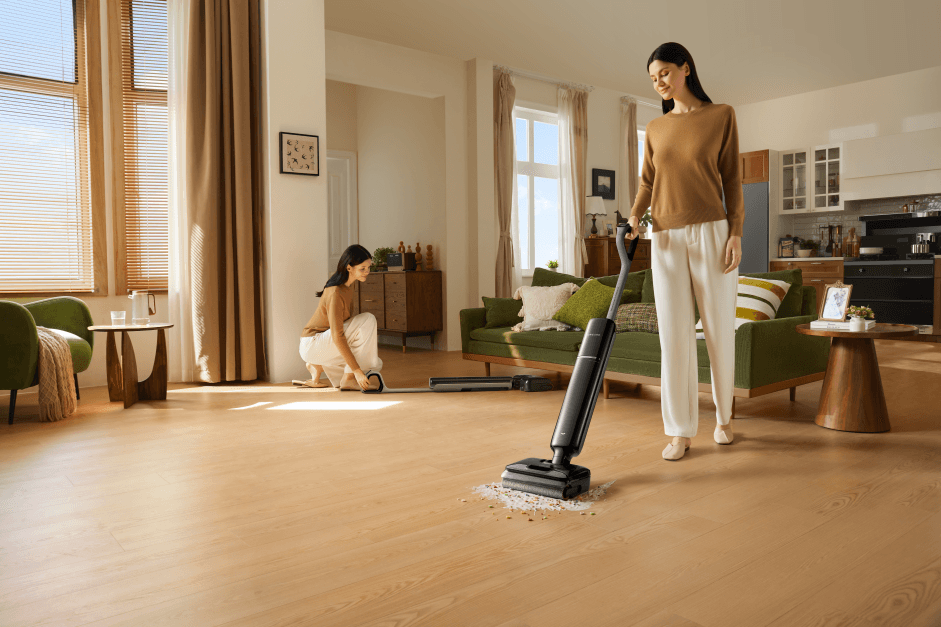 Femme utilisant un aspirateur laveur Dreame T Series noir sur un parquet, dans un salon moderne aux murs beiges et mobilier vert