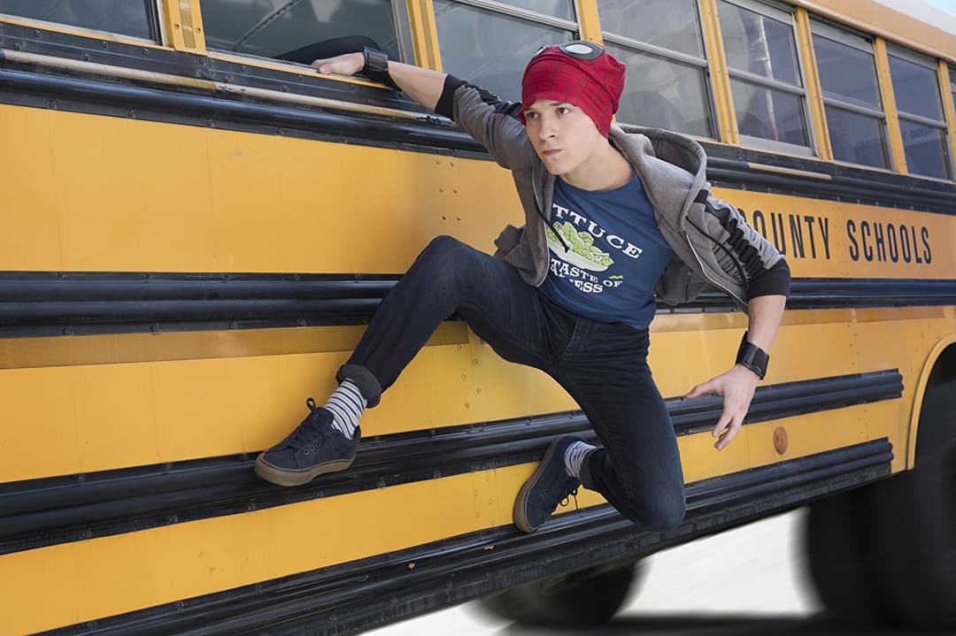 Adolescent assis sur le marche-pied d'un bus scolaire jaune, bonnet rouge et vêtements casual